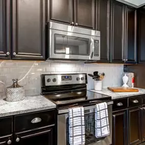 Kitchen with espresso cabinetry, burshed nickel hardware, stainless steel range and built in microwave