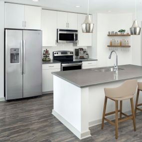 Two-bedroom kitchen with gray countertops, light cabinets, white backsplash and stainless steel appliances