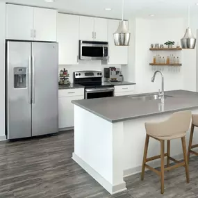 Two-bedroom kitchen with gray countertops, light cabinets, white backsplash and stainless steel appliances