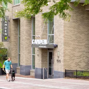 Resident walking dog by the front entry at Camden Music Row apartments in Nashville, TN