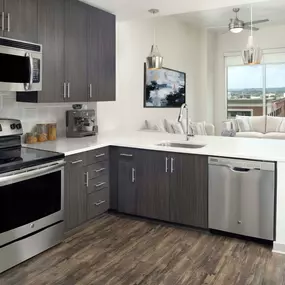 Kitchen with dark cabinets, light countertops, gray backsplash, stainless steel appliances and wood-style flooring throughout