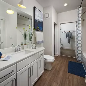 Relax in your Stunning Bathroom with Double Vanity Sinks, Subway Tile Showers with Glass Enclosures and Full Length Mirrors at Echo at North Pointe Center Apartment Homes