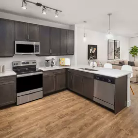 Flats one bedroom living room and large kitchen with brown cabinets and wood-style flooring at Camden Greenville