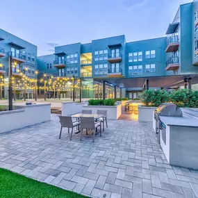 Courtyard at twilight with lit patio string lights and grill area at Camden Greenville apartments in Dallas, TX