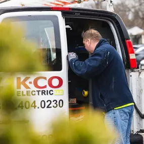 K-CO Electric technician accessing tools and materials from a fully equipped service van at a job site.