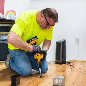 K-CO Electric technician installing a floor-mounted outlet box during an interior electrical upgrade.