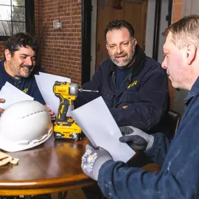 K-CO Electric team members reviewing project plans during a job site meeting, ensuring alignment and attention to detail.