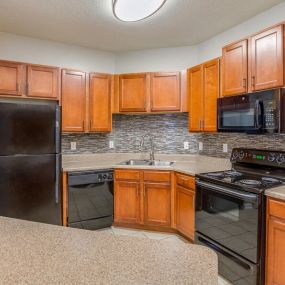 Open Floor Plan Kitchen with Wood Plank Vinyl Flooring (in Select Units) and Maple Raised-Panel Cabinetry