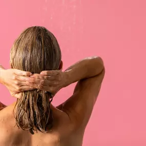 Person with medium length hair facing away from the camera. They are holding their hair back with both hands.