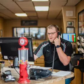 A technician helping a client get scheduled for some mechanical work on their car. Call or email us today!