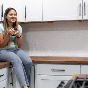 A girl sitting on the countertop after a cabinet painting service in Huntertown, IN