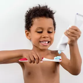 Young boy putting toothpaste on his toothbrush