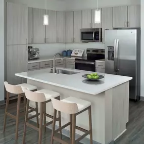 Kitchen with light gray cabinetry, white quartz countertops and stainless steel appliances.