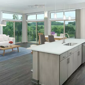 Large open kitchen and living room with light gray cabinetry and large windows opening to a balcony with a view.