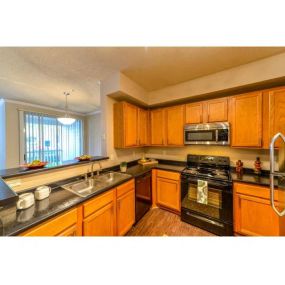 Open Kitchen with Custom Maple Cabinets, Stainless Steel Appliances and Breakfast Bar at Legacy Farm Apartments