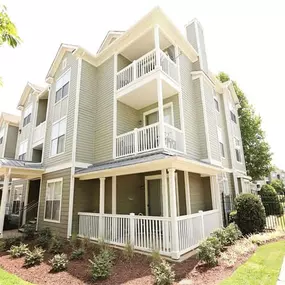 Meticulously maintained grounds with mature trees surround the soft green paint and brick exterior apartment homes at Legacy Farm Apartments