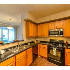 Open Kitchen with Custom Maple Cabinets, Stainless Steel Appliances and Breakfast Bar at Legacy Farm Apartments