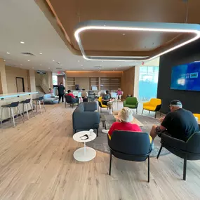 The interior of the new Jeff Wyler Kia of Colerain building, showcased in this photo, features multiple seating areas, a television, and charging ports, adding to the exceptional customer service when waiting to purchase new or used vehicles near Cincinnati, Ohio.