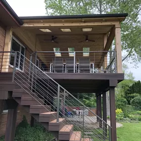 Covered lakefront deck with ceiling, metal railings, and a spacious dining area overlooking a serene landscape