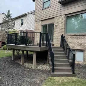 Raised composite deck with black metal railings and a staircase