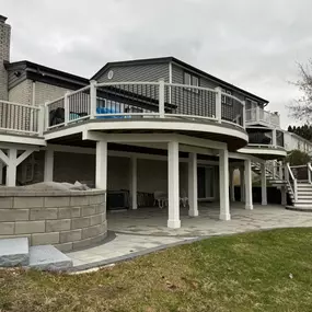 Elevated deck with white posts and dark railings, featuring a covered patio area.