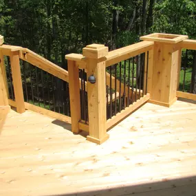 Custom cedar deck with railing overlooking a lush green backyard