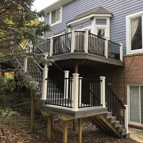 Multi-level elevated deck with black metal and white post railings, featuring a staircase