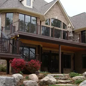 Spacious elevated composite deck with black metal railings and covered patio in Commerce Charter Twp, MI. Built by Cedar Works, this design blends elegance, durability, and expanded outdoor living space.