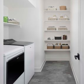 Laundry room with full-size washer and dryer and built-in wood shelves at Camden Durham apartments in Durham, NC.