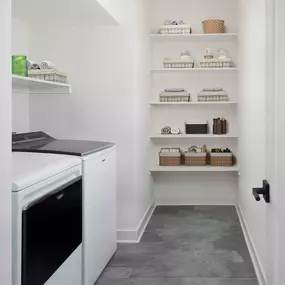 Laundry room with full-size washer and dryer and built-in wood shelves at Camden Durham apartments in Durham, NC.