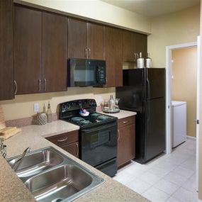 New Kitchens with Ceramic Tile Flooring, Custom Upgraded Cabinetry and Sleek Black Appliances at Courtney Bend Apartment Homes