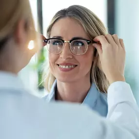 Optometrist placing a pair of glasses on a female patient.