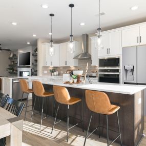 Gourmet kitchen with white cabinets, wood tone island and stainless steel appliances in the DRB Homes Recess Pointe community