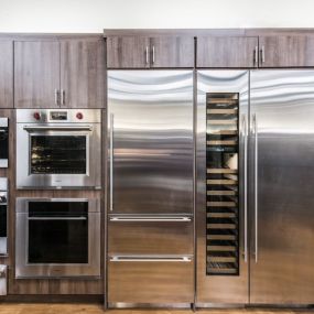 Kitchen Appliance showroom with built-in stainless steel wall ovens, refrigerators, microwaves, and wine coolers