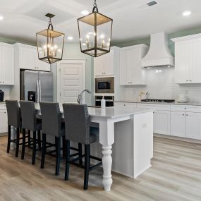 Gourmet kitchen with island with white cabinets in the DRB Homes Saddleridge community