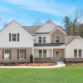 New construction 2-story brick front home with white siding in the DRB Homes Saddleridge community