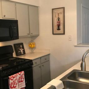 Galley kitchen with black appliances and side by side sink.