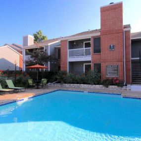 Large blue swimming pool with spacious sundeck and chairs.