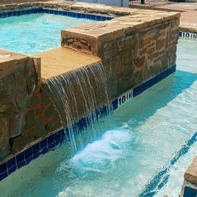 Large rectangular spa with stone waterfall.