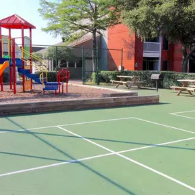 Fenced in playground and sports area with picnic tables.