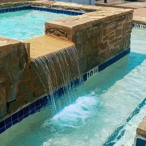 Large rectangular spa with stone waterfall.