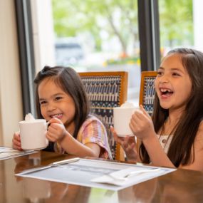 Two children smiling and enjoying hot chocolate at the Little America Hotel.