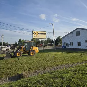 Volvo compact loader parked near Chadwick-BaRoss sign and building