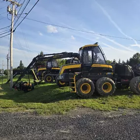 Ponsse forestry equipment lined up on grass near the road