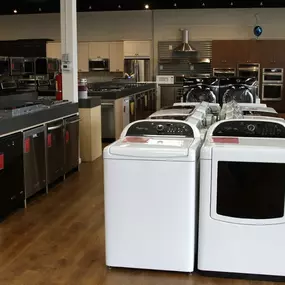 Appliance show room with dishwashers and laundry appliances lined up for display and wooden flooring