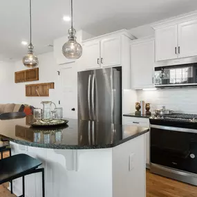 Kitchen with white cabinets and spacious island with two bar stools at DRB Homes Trailside at Drayton Mills community