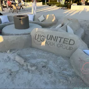 United Aqua Group Logo carved into sand at the 2024 Marco Island Annual Conference.