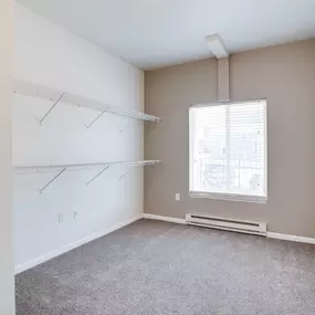 an empty room with white walls, shelves and a window