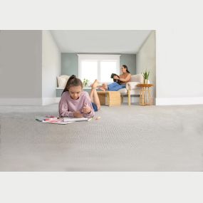 Young girl laying on the clean carpet coloring