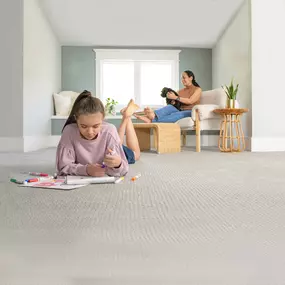 Young girl laying on the clean carpet coloring